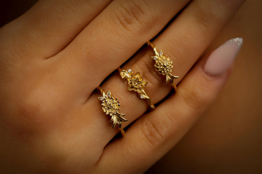 3 birth flower rings in gold on a finger