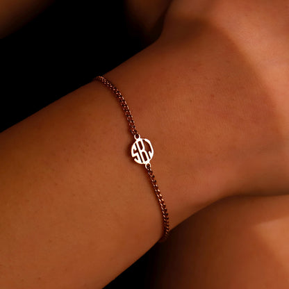 A close-up image of a person's wrist wearing a ROSE gold-filled bracelet with a block monogram initial pendant.