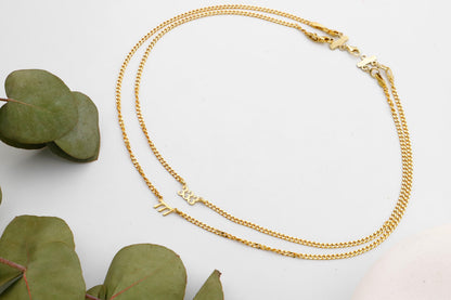 A close-up image of a layered gold intertwined necklace with the numbers '333' and '777' on small, dainty chain links.