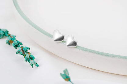 A close-up image of a silver stud bubble  heart-shaped earring.