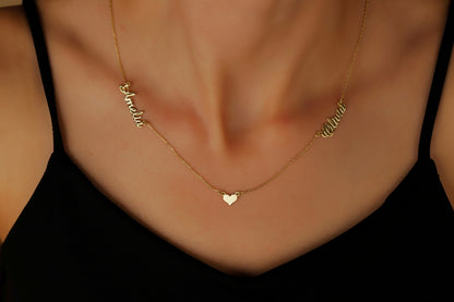 A close-up image of a gold necklace with two names and a heart pendant, worn by a person.