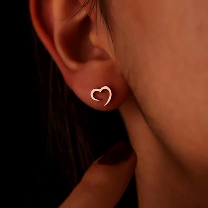Close-up of an ear wearing a heart-shaped earring with a blurred background.