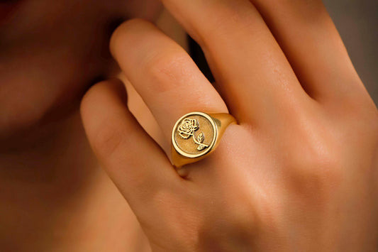 Gold ring with a design on a person's finger against a blurred background