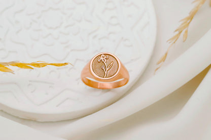 Rose gold ring with floral design on a textured white surface
