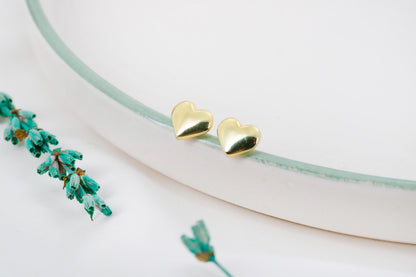 A close-up image of a gold stud bubble  heart-shaped earring.