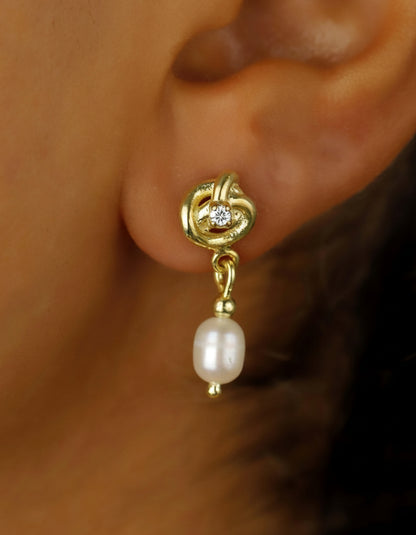 Gold earring with a pearl and diamond on an ear