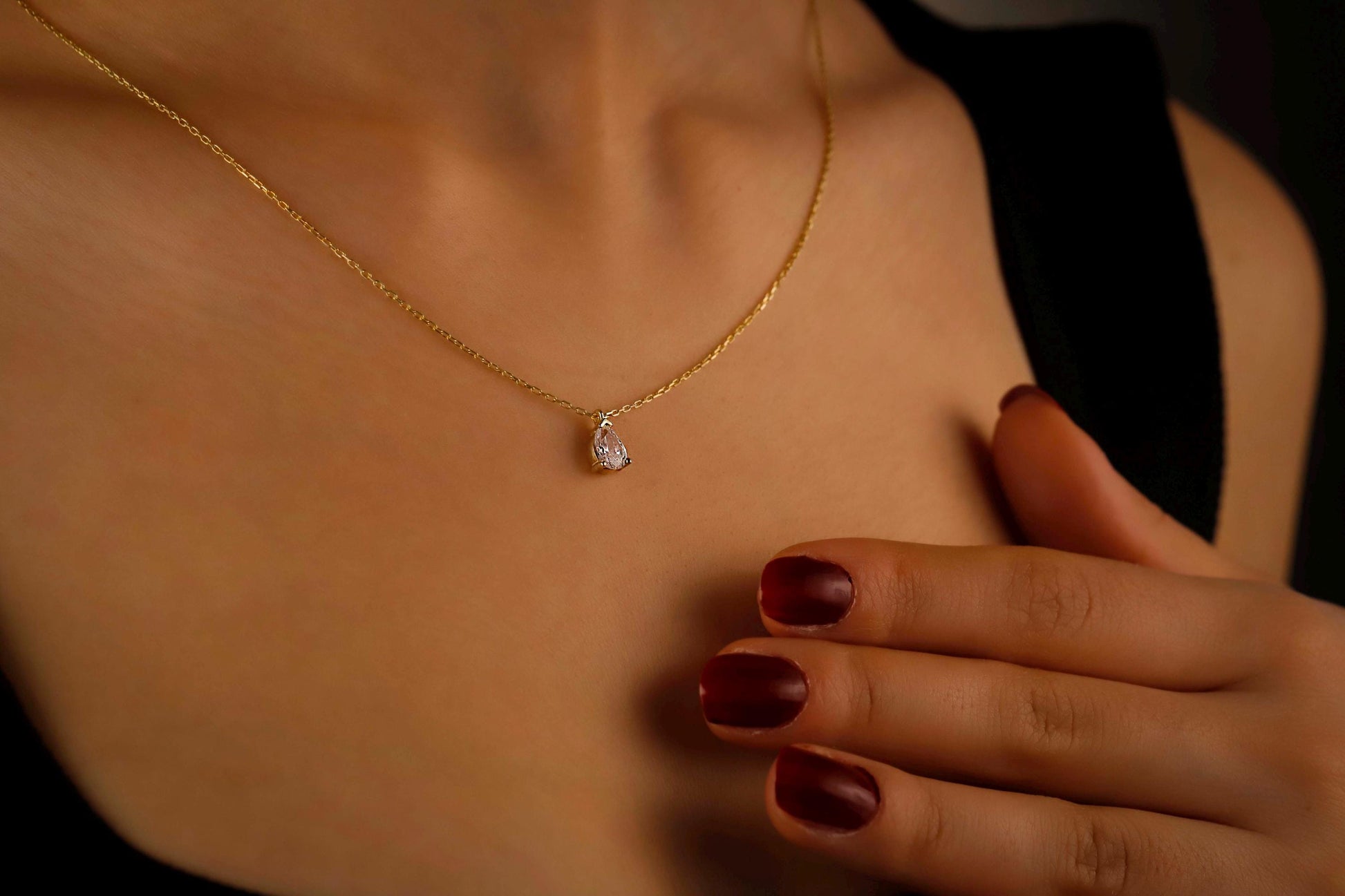Gold necklace with a heart-shaped pendant worn by a person