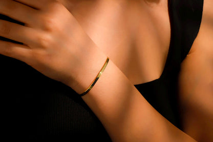 Gold bracelet on a wrist with a blurred background