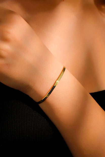 Gold bracelet on a wrist with a blurred background