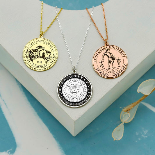 Three university-themed necklaces on a white stand with a blue background