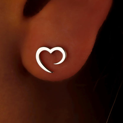 Silver heart-shaped earring on a person's ear