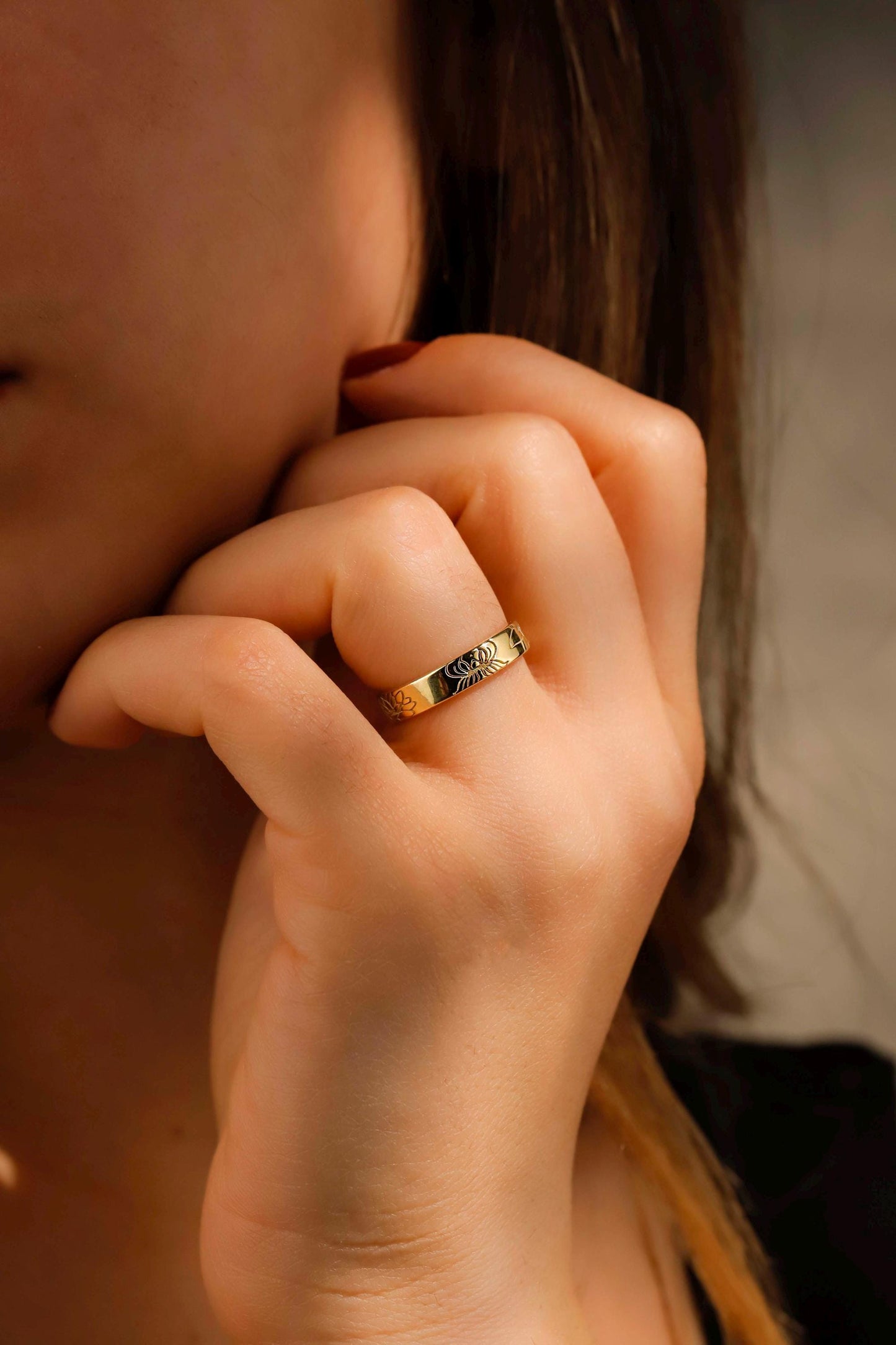Close-up of a hand with a gold ring on a blurred background