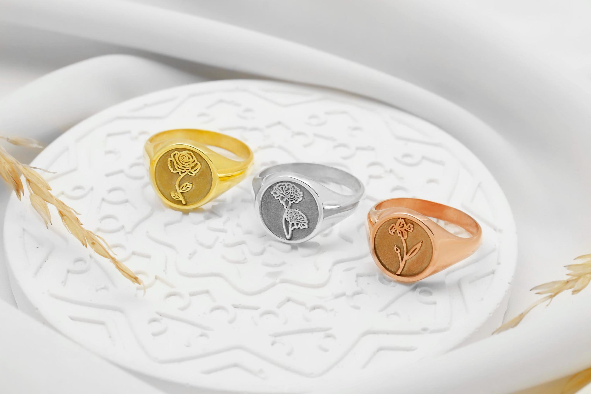 Three rings in gold, silver, and rose gold on a decorative white dish.
