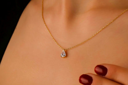Gold necklace with a pendant on a person's neck against a neutral background