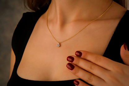 Gold necklace with a pendant worn by a person, with a blurred background