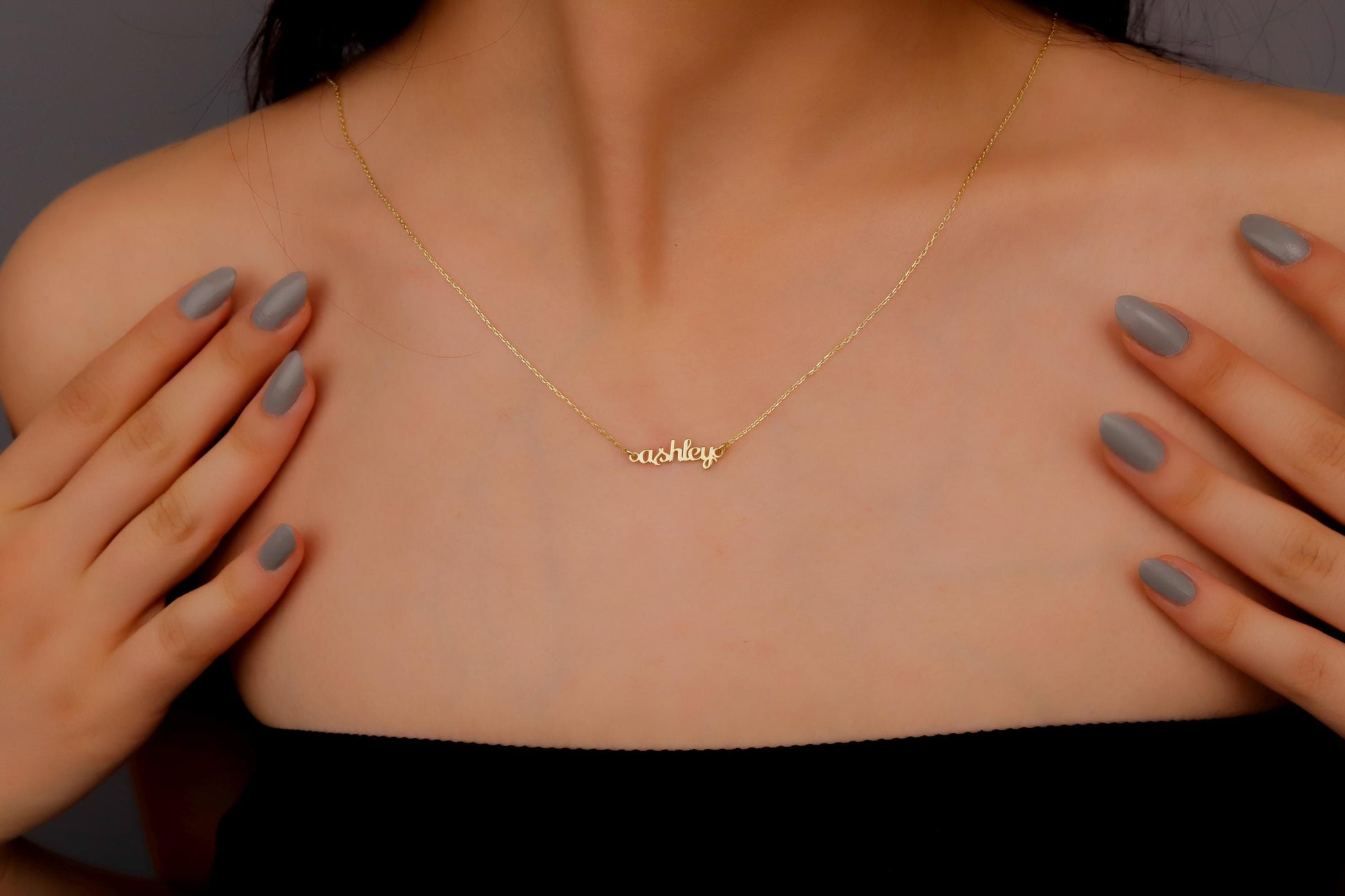 Gold necklace with 'aisha' on a person's neck
