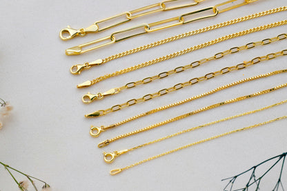 Gold chains of various designs on a light gray background
