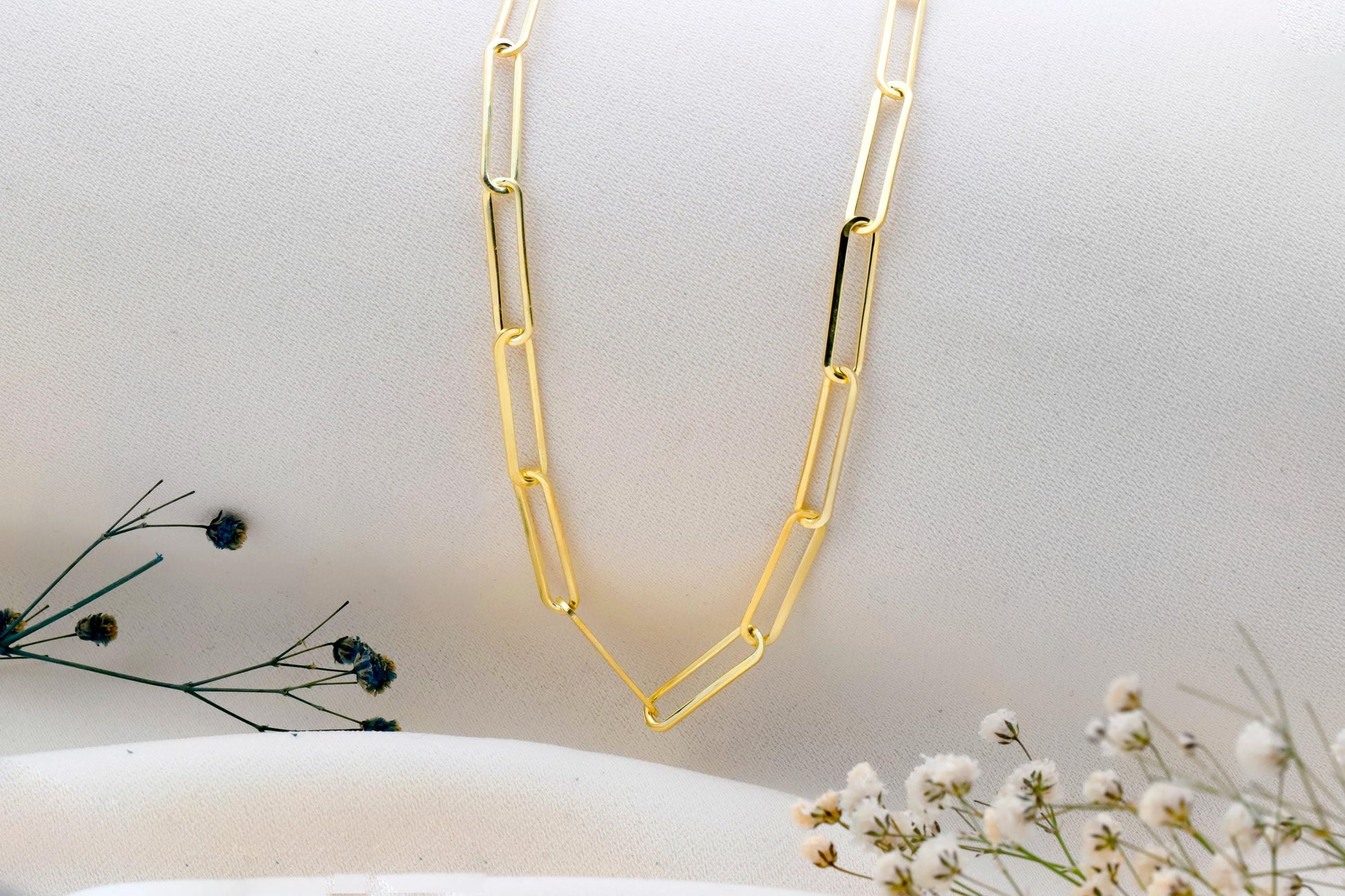 Gold chain necklace on a white surface with minimal background