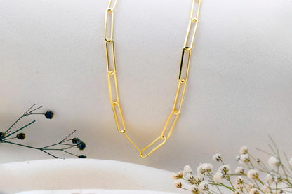 Gold chain necklace on a white surface with minimal background