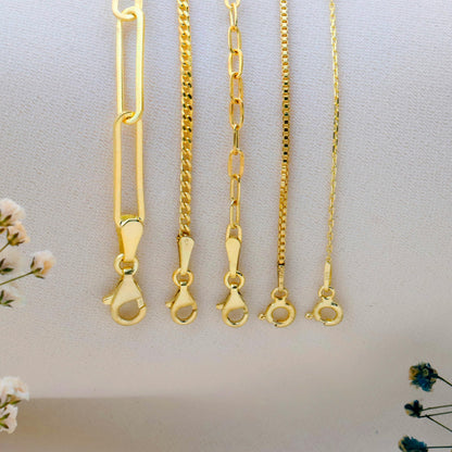 Set of gold necklaces on a light gray background with small flowers.