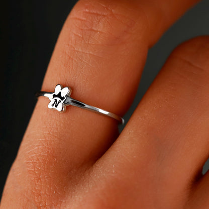 Silver ring with a small dog design on a person's finger against a dark background