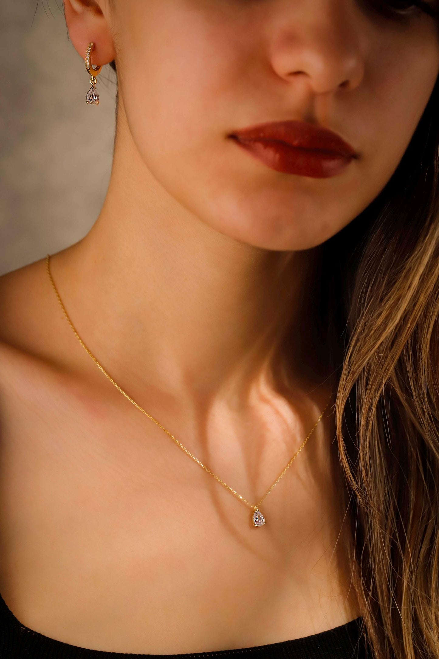 Close-up of a woman wearing a gold necklace with a small pendant.