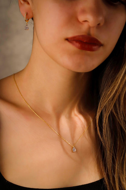 Close-up of a woman wearing a gold necklace with a small pendant.