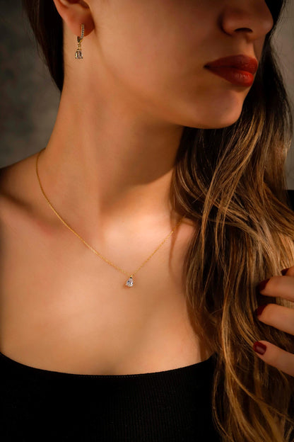Close-up of a woman wearing a gold necklace with a small pendant.