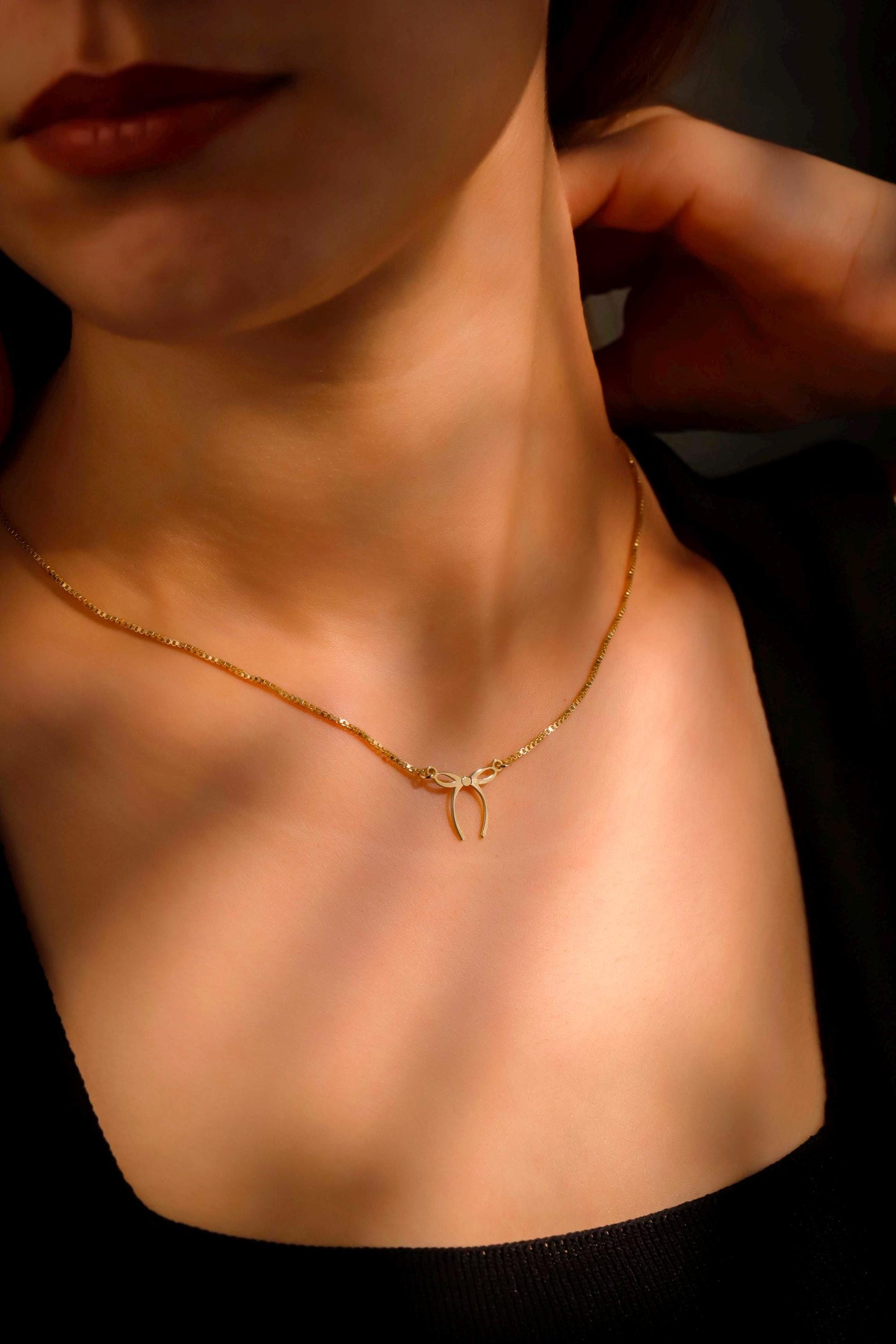 Close-up of a person wearing a gold necklace with a dark background
