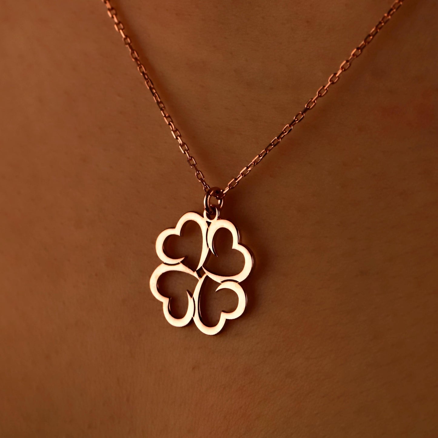 Gold four-leaf clover pendant on a chain against a brown background