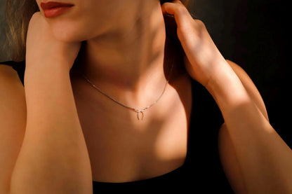 Close-up of a person wearing a delicate necklace with a dark background