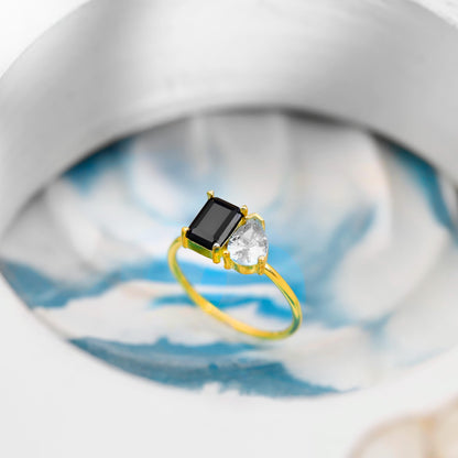 Gold ring with a black gemstone and clear stones on a blurred background