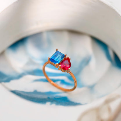 Ring with blue and red gemstones on a marble surface