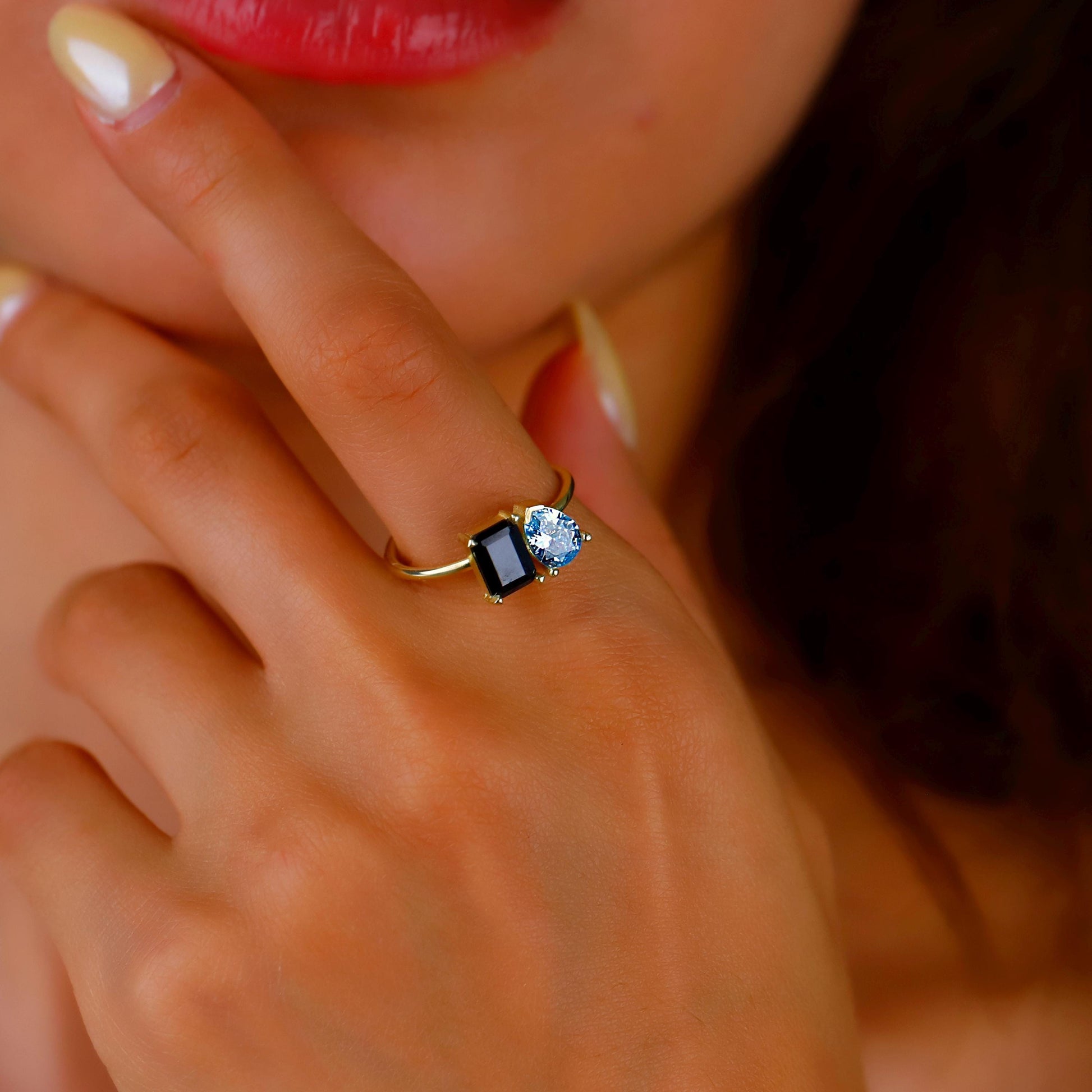 Close-up of a hand wearing a gold ring with a blue gemstone.