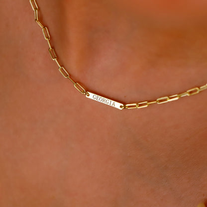 Gold chain necklace with 'GEORGIA' engraving on a skin background