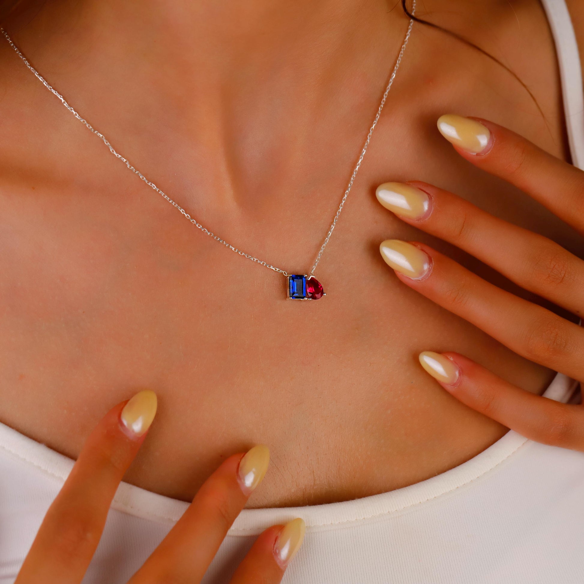 Necklace with a gemstone pendant worn by a person, with hands adjusting the necklace.