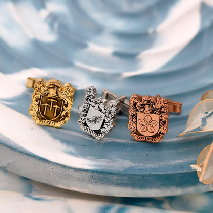 Three cufflinks with engraved designs on a textured blue surface