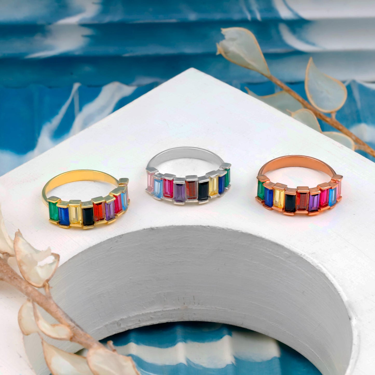 Three colorful rings on a white surface with a blue water background