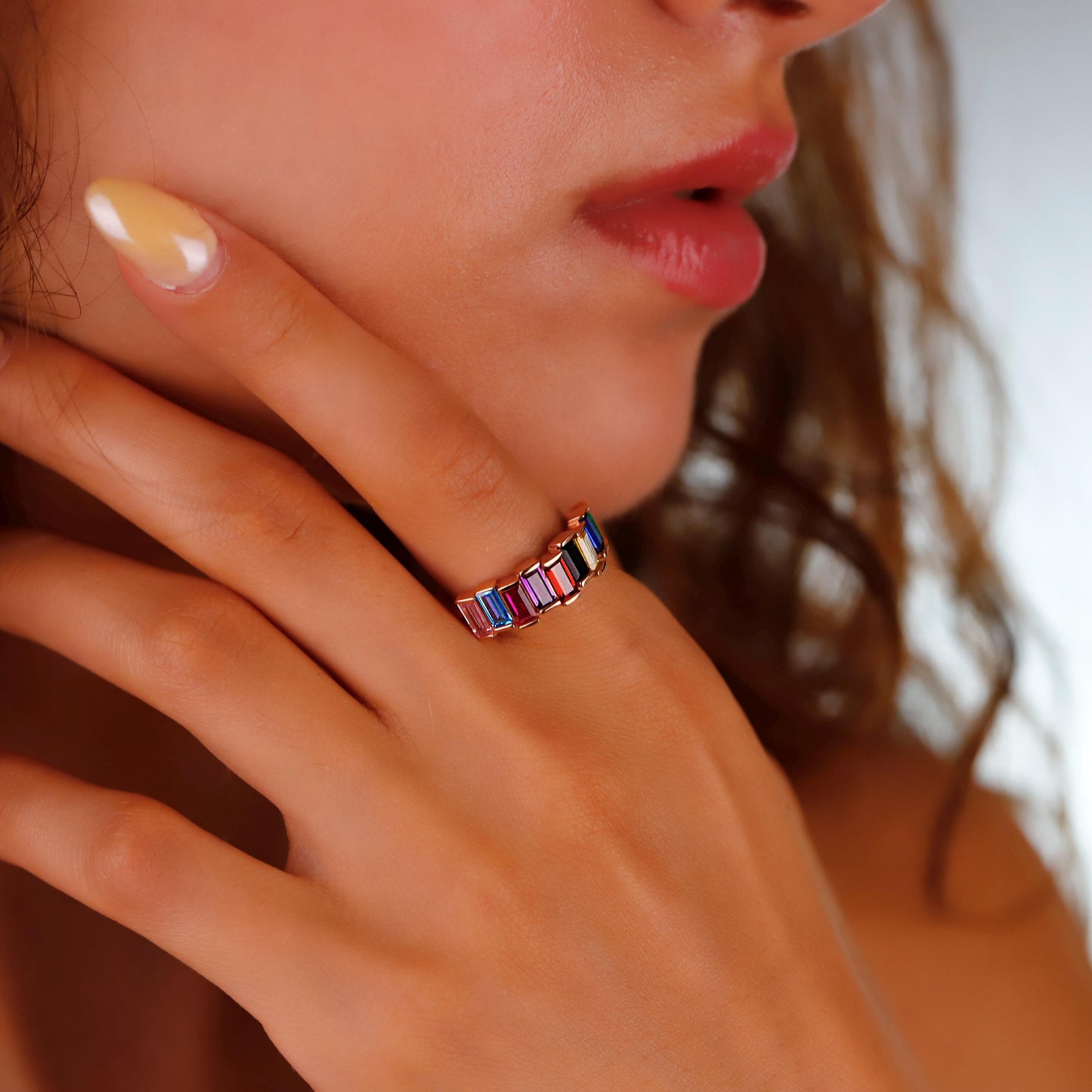 Close-up of a hand wearing a colorful ring with a blurred background