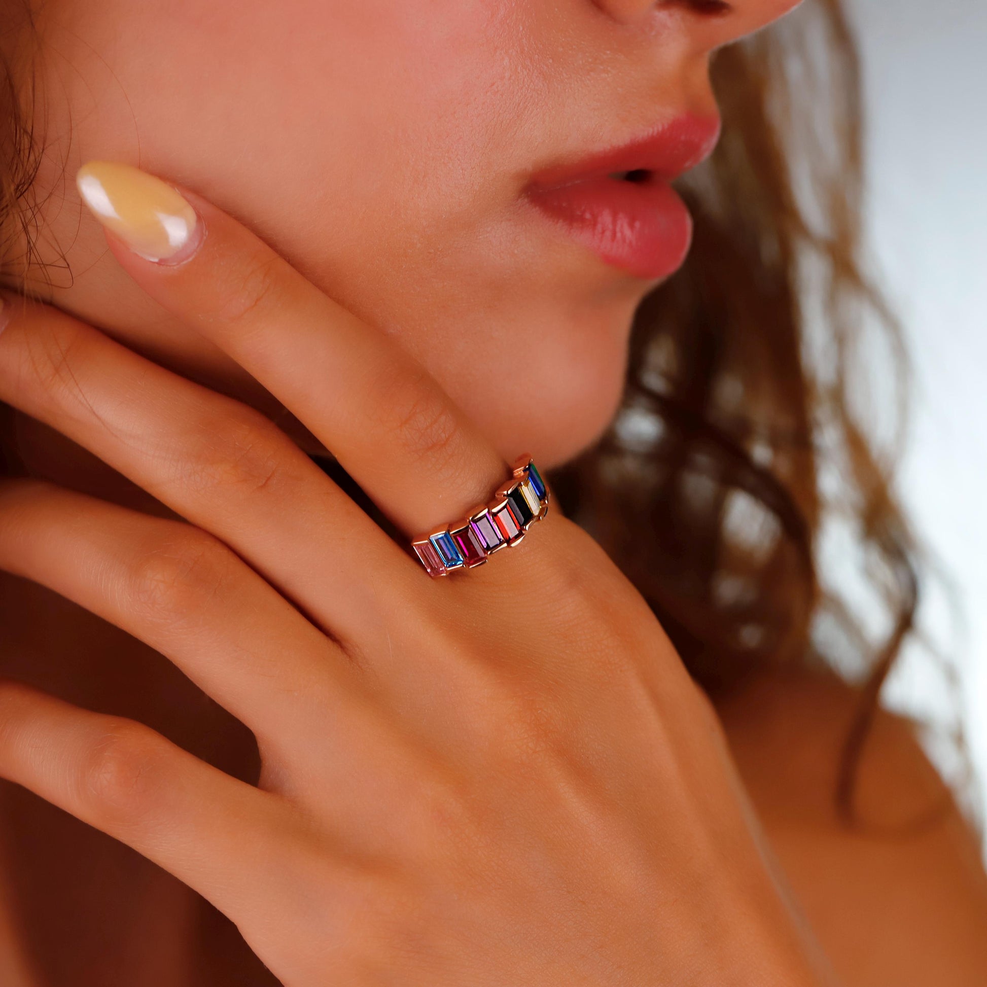 Close-up of a hand wearing a colorful ring with a blurred background