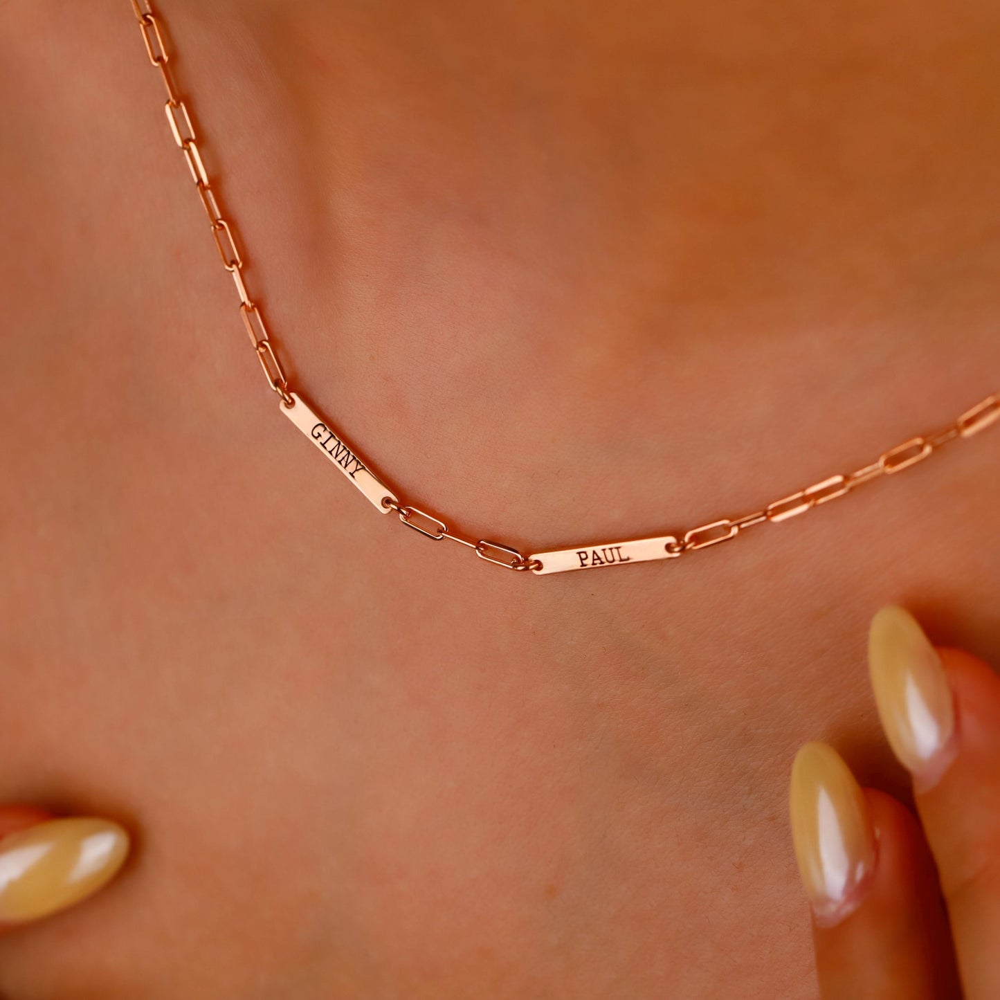 Rose gold necklace with engraved names on a person's neck