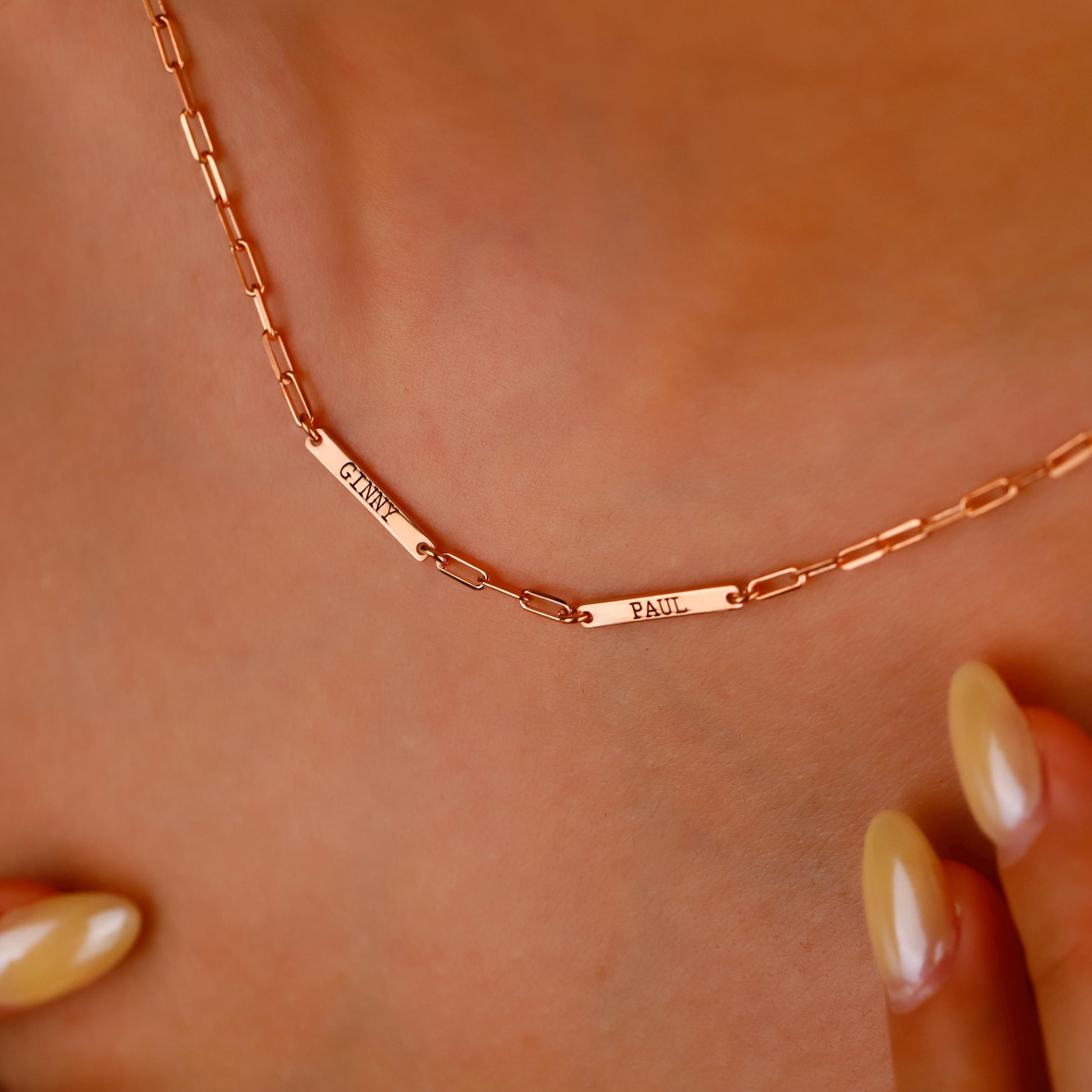 Rose gold necklace with engraved names on a person's neck