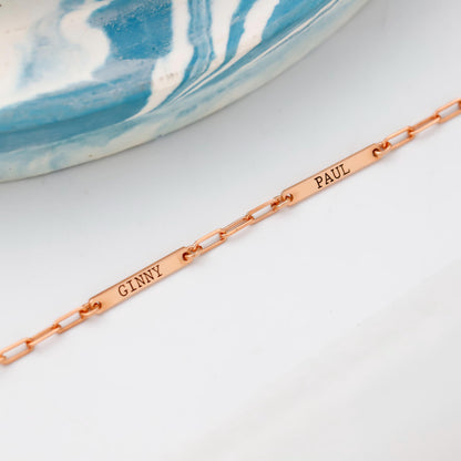 Rose gold bracelet with engraved names on a white surface