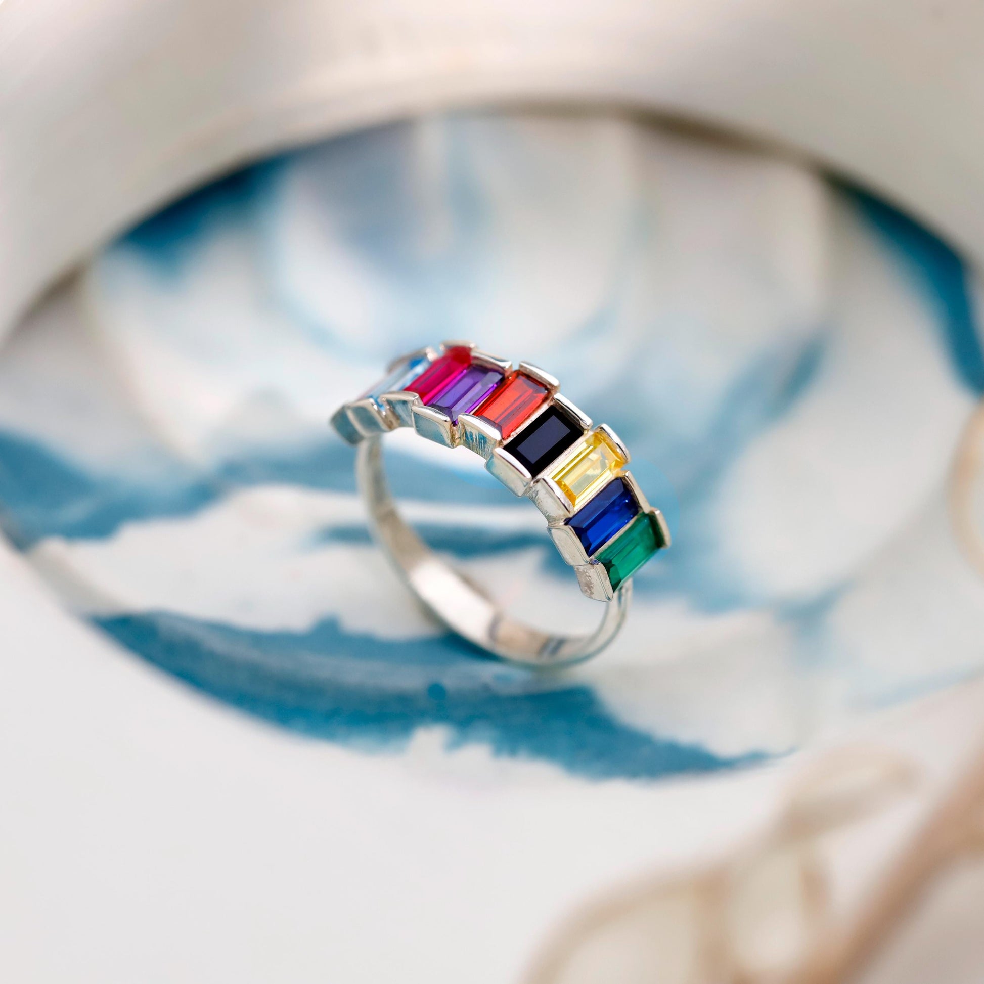 Ring with colorful gemstones on a white and blue patterned background