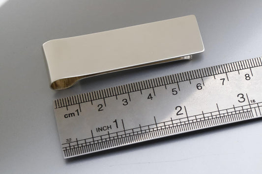 Silver money clip on a ruler for size reference
