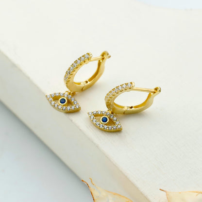 Gold earrings with blue gemstones on a white surface