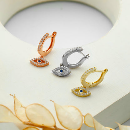Three pairs of earrings in rose gold, silver, and gold on a decorative surface.