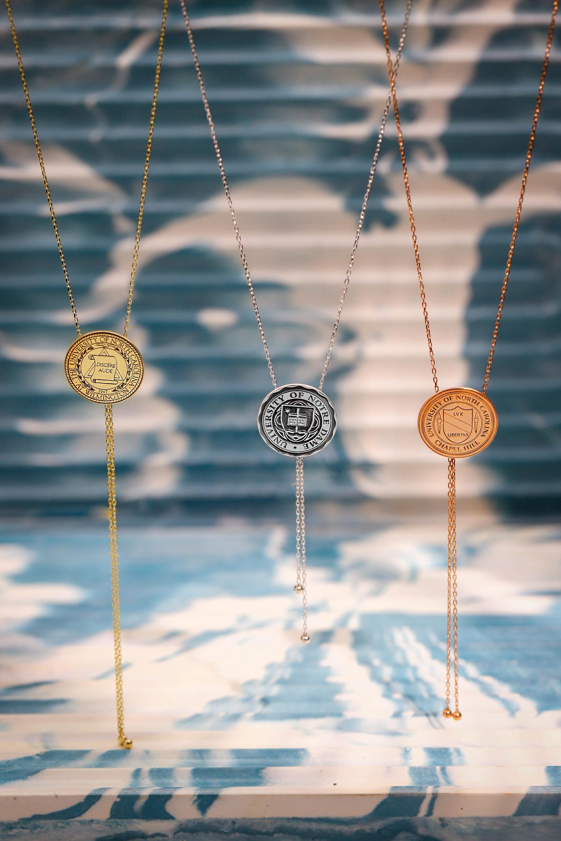 Three necklaces with circular pendants on a blue and white patterned background