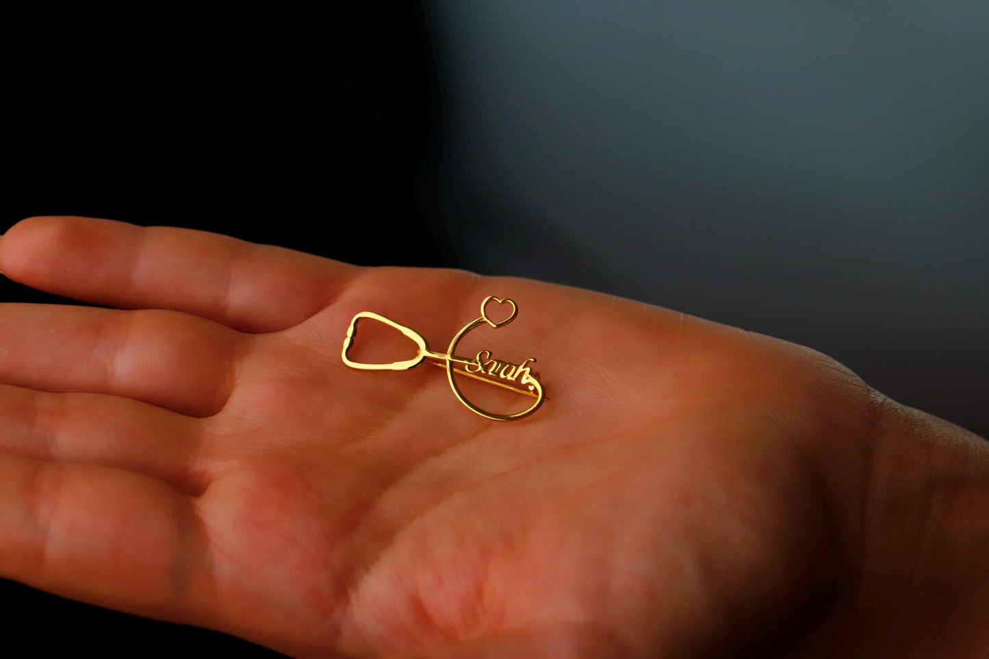 Gold infinity symbol ring on a person's palm with a dark background