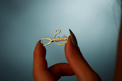 Gold eyeglass frame with 'Swarovski' branding held between fingers against a blue background